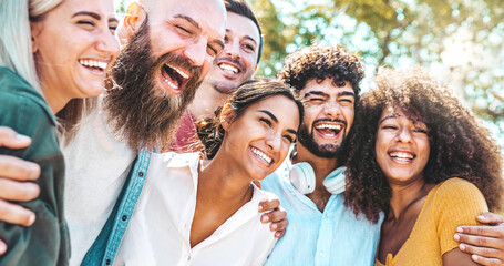 Multicultural group of friends enjoying summertime vacation hanging outside together - University...