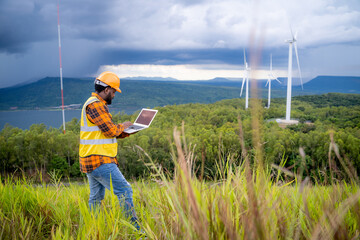 Portrait of engineer African American man working with laptop in wind turbine farm.
