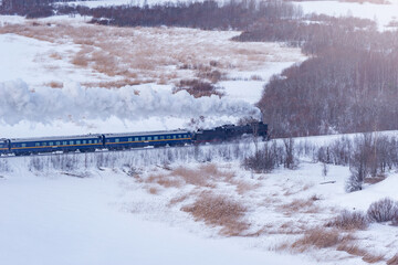 Retro steam train moves at winter morning.