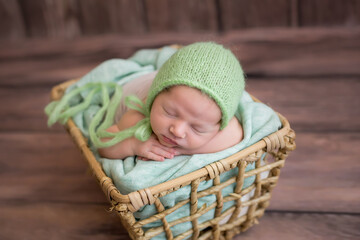 sleeping newborn in a hat lies on a basket