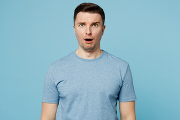 Young sad shocked surprised scared caucasian european man wearing casual t-shirt look camera with opened mouth isolated on plain pastel light blue cyan background studio portrait. Lifestyle concept.