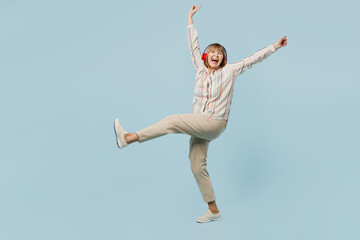 Full body elderly oman 50s years old wear striped shirt headphones dance raise up hands have fun on party isolated on plain pastel light blue cyan color background studio portrait. Lifestyle concept.