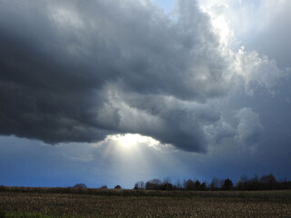 Fototapeta na wymiar Storm clouds with rays of sunshine beaming down upon a field in Cecil County, Maryland.