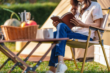 Asian woman reading a book enjoying camping outdoors in nature. traveling in the wild.