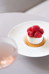 Elegant set table with raspberry dessert and a glass of champagne. Trendy interior background. Selective focus.