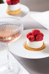 Elegant set table with raspberry dessert and a glass of champagne. Trendy interior background. Selective focus.