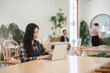 Portrait of beautiful asian woman freelance using laptop for online workingat cafe.