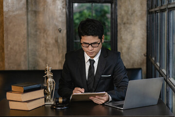 Asian young lawyer working with laptop and hammer with scales giving online legal advice explaining contract rules to legal advisor and justice office concept