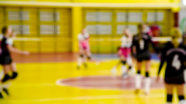 Group of teen girls playing indoor volleyball. Blurred