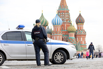 Woman police officer patrol a Red Square in Moscow in spring standing near the car and St Basil...