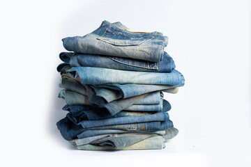 Stack of various shades blue jeans. Jeans stacked isolated on white background. Blue denim jeans texture banner with copy space for text design background. Canvas denim fashion texture