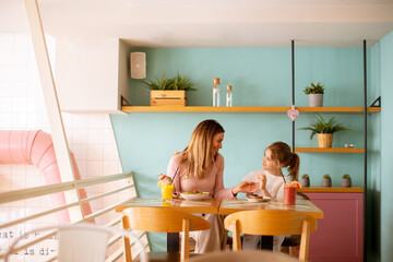 Mother and daughter having a breakfast with fresh squeezed juices in the cafe