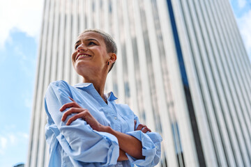 Businesswoman smiling while standing proud with arms crossed outdoors - Powered by Adobe
