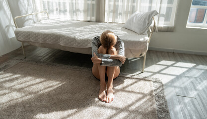 the depressive woman sits on the floor feeling hopeless alone and depressed after break up with her...