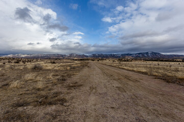 Fototapeta na wymiar Dirt road in foreground leading to gorgeous mountain range in high desert