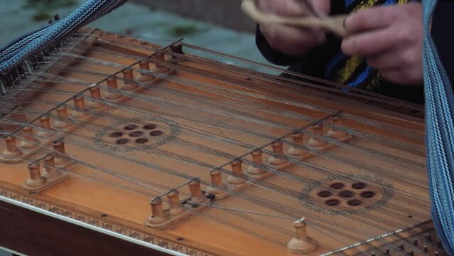 Plays the musical instrument dulcimer. Wooden bat. Playing traditional musical instruments. Human hands play cymbals.