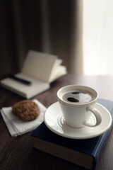 Still life. White cup with coffee and cookies on the table near the window