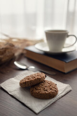 Still life. White cup with coffee and cookies on the table near the window