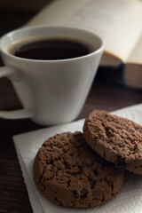 Still life. White cup with coffee and cookies in front of an open book with poetry