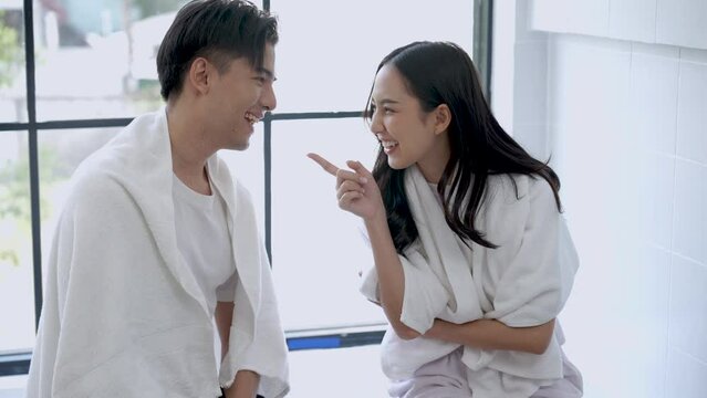 Happy Asian couple talking and laughing together in the bathroom in the morning.