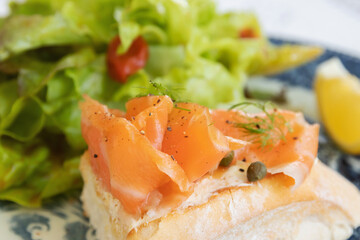 Smoked salmon with cream cheese on french baguette and fresh salad.