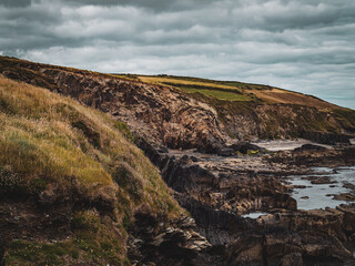 Picturesque landscape. Wild vegetation on stony soil. Cloudy sky. Views on the wild Atlantic way, hills under clouds.