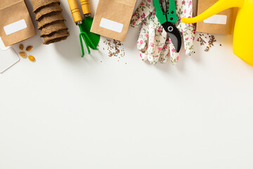 Flat lay composition with garden tools on white background. Frame made of peat pots, seed packets,...