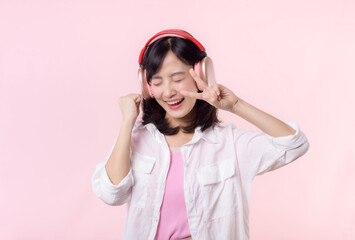Smile pretty asian model person listen music song and enjoy dance with wireless headphone online audio radio sound. Positive fun exited joyful youth female woman on pink isolated background studio