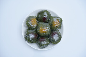 A plate of Qingtuan stuffed with egg yolk and dried meat floss isolated on white background. Traditional seasonal Chinese delicacies in Jiangnan area around the time of Tomb Sweeping Day. 