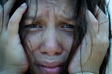 A close up of a sad woman’s face and eyes looking into the camera in despair.