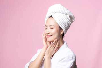 Beautiful young asian woman happy with clean face skin in towel and bathrobe, spa suit on pink...