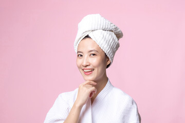 Beautiful young asian woman happy with clean face skin in towel and bathrobe, spa suit on pink background. Skincare, treatment, wellness therapy, facial care, beauty female health, cosmetology concept