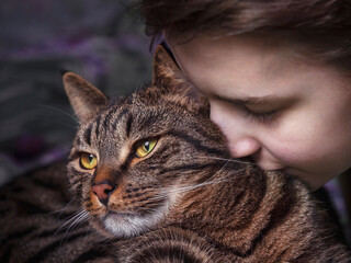 A teenage boy hugging a striped cat