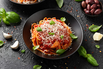 Italian marinara sauce spaghetti pasta served with fresh basil, olives and pecorino cheese