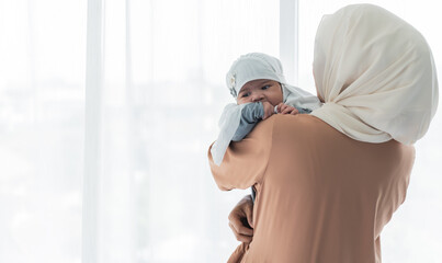 Muslim family, an Asian mother holding baby newborn girl is 2-month-old. standing on white...