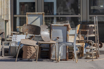 old broken chairs and a rusted iron box thrown into the trash