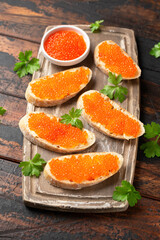 Salmon red caviar sandwiches on wooden board