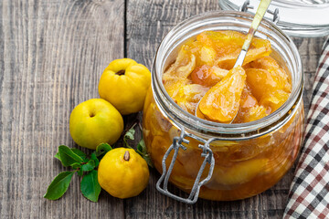 Naklejka na ściany i meble Homemade quince jam in glass jars and fresh quince with leaves on wooden table
