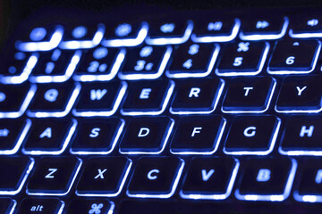 Macro closeup of electronic LED back lit keyboard, blue and white lighting 