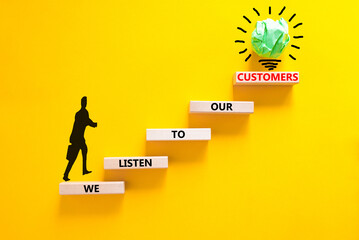 We listen to our customers symbol. Concept words We listen to our customers on wooden block. Beautiful yellow background. Businessman icon. Business we listen to our customers concept. Copy space.