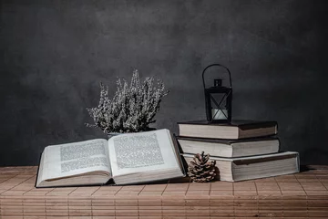 Foto op Plexiglas otwarta książka i stos książek z kagankiem w kompozycji martwa natura © Henryk Niestrój