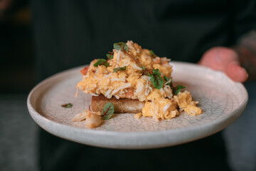 A plate with an omelet with crab meat, seafood, toast and herbs. Serving dishes, close-up