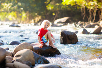 Child hiking in mountains. Kids at river shore.
