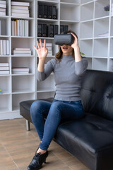 Fototapeta na wymiar Smiling woman having fun using VR glasses playing game at home happily and enjoy virtual reality.
