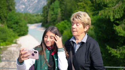 A young girl taking a selfie with her grandmother along a mountain river - Powered by Adobe