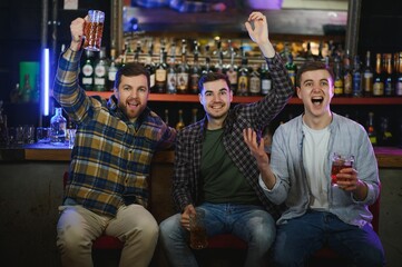 Obraz premium Soccer fans at the bar. Happy football fans cheering at bar and drinking beer while bartender serving beer at the background