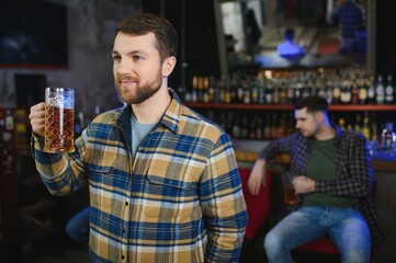 Tasting a good beer. Portrait of thoughtful men drinking beer at the bar