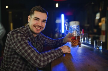 Night in bar. Portrait of cheerful men drinking beer at the bar