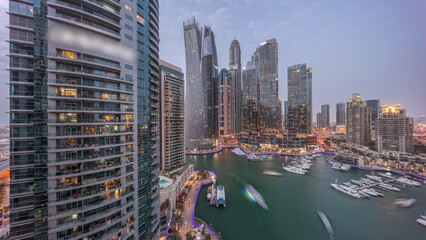 Dubai marina tallest skyscrapers and yachts in harbor aerial day to night timelapse.