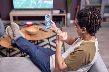 High angle view at young man watching football match at home and winning online bet